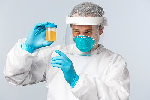 Covid-19, preventing virus, healthcare workers and vaccination concept. Medical employee, nurse or doctor in personal protective equipment examine urine sample of patient.