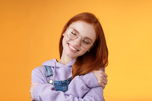 Lifestyle. Close-up romantic lovely charming redhead girl enjoy warmth love tilting head close eyes dreamy imaging perfect date hugging herself embracing own body accept body-positivity orange background.