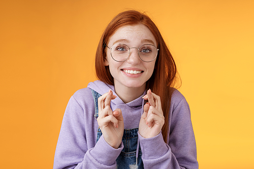 Hopeful young cute silly dreamy redhead attractive girl ginger straight haircut wearing glasses begging lord help cross fingers good luck desire win dream come true praying wish fulfill. Lifestyle.