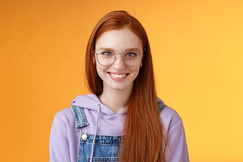 Good-looking redhead female programmer glasses hoodie smiling satisfied look professional aim success standing confident grinning delighted camera talking casually orange background.