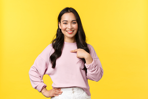 People emotions, lifestyle and fashion concept. Confident pretty and stylish asian woman in casual outfit pointing herself, propose own candidature, smiling pleased, stand yellow background.