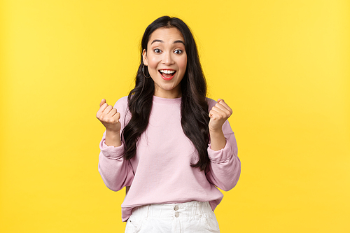 Lifestyle, emotions and advertisement concept. Cheerful and excited cute asian girl winning lottery, feel luck and upbeat, triumphing over achievement, say yes and fist pump rejoicing.