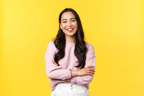 People emotions, lifestyle and fashion concept. Cheerful good-looking korean girl having fun, laughing out loud and feeling happy, standing joyful over yellow background.