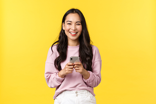 People emotions, lifestyle leisure and beauty concept. Happy and surprised pretty korean girl in stylish outfit, looking amazed with broad smile camera after reading great news in mobile appplication.