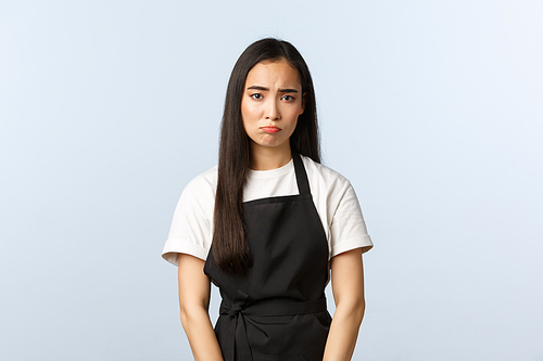 Coffee shop, small business and startup concept. Gloomy and sad cute asian barista, female cafe staff sulking, feeling distressed or exhausted, have unhappy expression, white background.