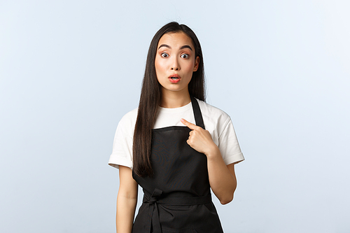 Coffee shop, small business and startup concept. Surprised clueless silly newbie at cafe pointing herself with puzzled expression. Cute asian waitress or barista being chosen.