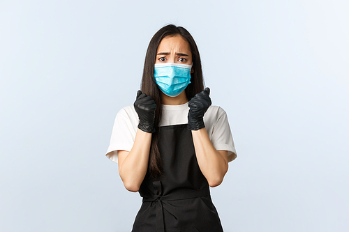 Covid-19 pandemic, social distancing, small business and preventing virus concept. Worried female asian barista scared of client coughing during coronavirus outbreak, wear medical mask and gloves.