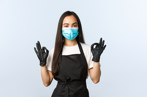 Covid-19, social distancing, small coffee shop business and preventing virus concept. Employee have all under control, guarantee quality, show okay sign, wearing medical mask and gloves.
