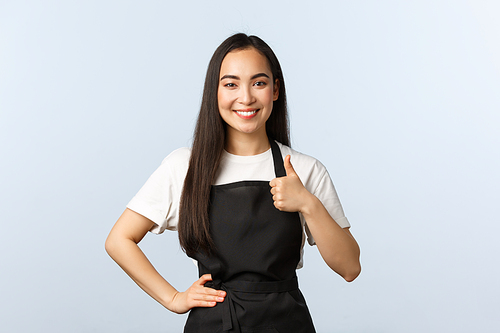 Coffee shop, small business and startup concept. Smiling friendly asian waitress in black apron show thumb-up. Cute barista guarantee best quality of drinks at her cafe.