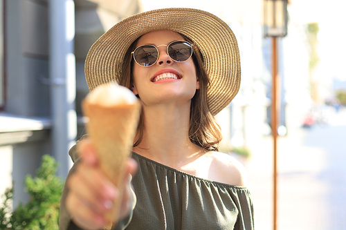 Happy attractive girl enjoying an ice cream while walking outdoor