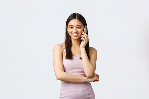 Luxury women, party and holidays concept. Smiling pretty korean girl talking on phone, happy mobile conversation with friend, hold smartphone and looking camera, wear evening dress.