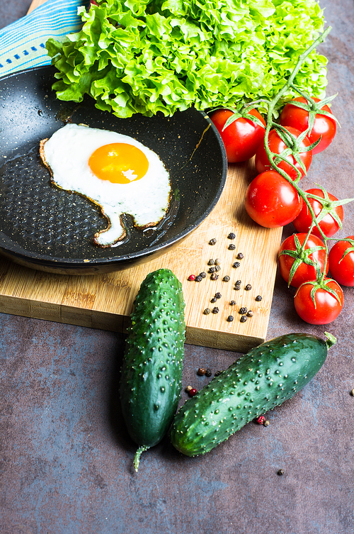 Breakfast with fried egg, cherry-tomatoes and spices on rustic kitchen table