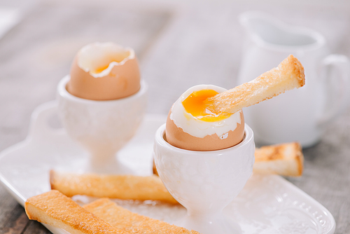 delicious breakfast with soft boiled eggs and crispy toasts, closeup