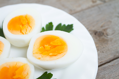 Sliced hard boiled eggs with parsley on a white plate, close-up