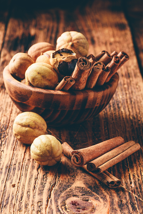 Cinnamon sticks and dried limes in wooden bowl on rustic table