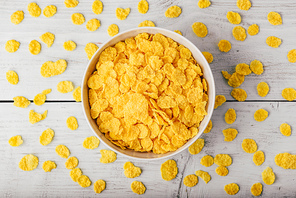White bowl of corn flakes on a wooden surface