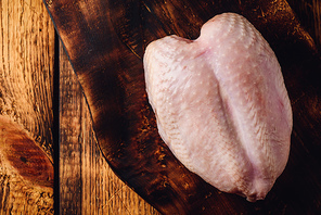 Raw chicken breast on rustic chopping board