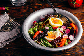 Fresh spring salad with tomato, radish, cucumber, red leaf lettuce and boiled eggs in metal bowl