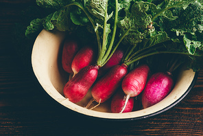 Bowl of homegrown red radish on wooden table