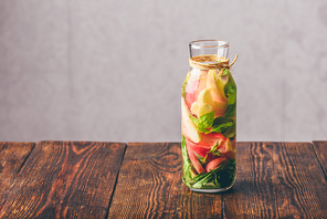 Bottle of Infused Water with Sliced Peach and Basil Leaves.