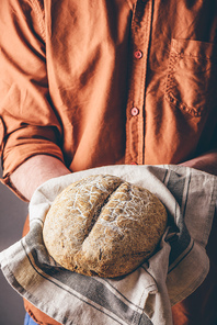 Man holds a loaf of freshly baked rye bread