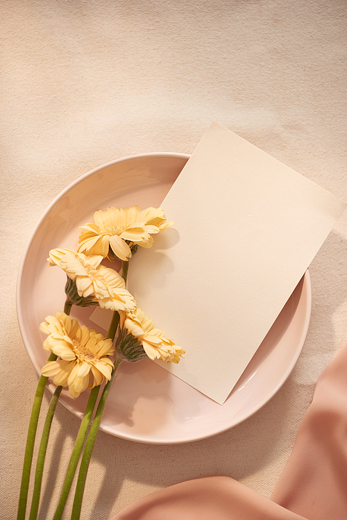 Flowers on plate with card and fabric on the light background