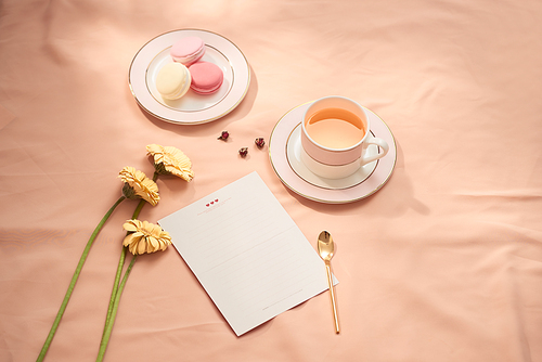 Envelope, flowers, and macarons with cup of tea