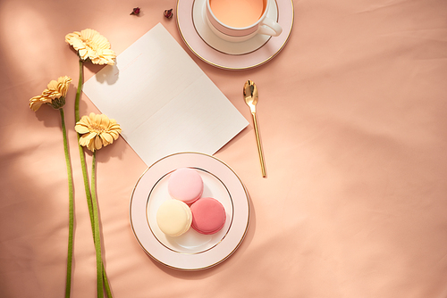 Envelope, flowers, and macarons with cup of tea