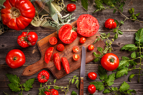 Cutting red tomatoes composition background as knife and tomato bunch on the wooden cutting board
