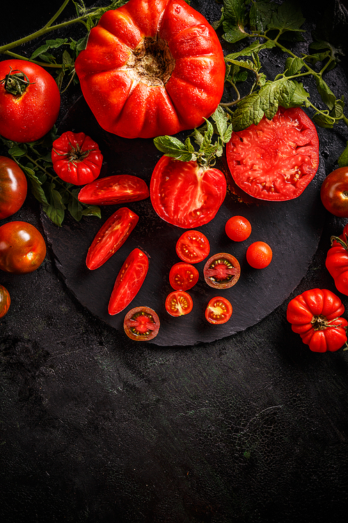 Cutting red tomatoes composition background as knife and tomato bunch on the black background
