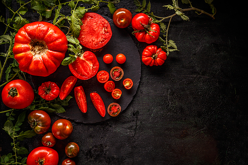 Fresh red sliced and whole tomatoes on black background, space for your text