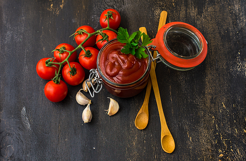 Tomato ketchup sauce in a bowl with spices, herbs and cherry tomatoes. View from above.