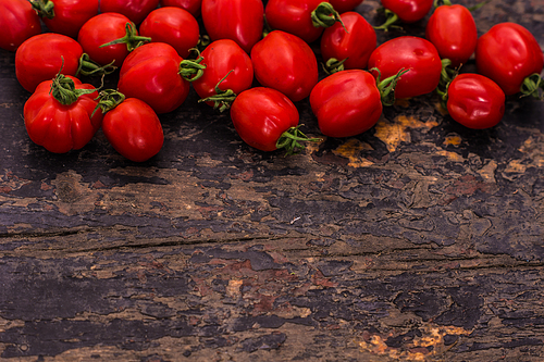 Fresh ripe organic cherry tomatoes and bright ceramic plates on dark wooden table wt copyspace