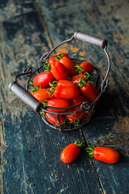 Ripe organic cherry-tomatoes on dark rustic wooden table with copyspace