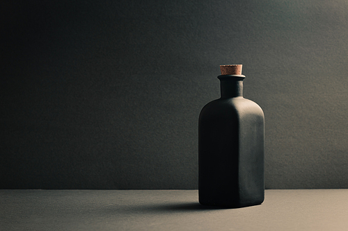 A single black ceramic bottle over a dark background