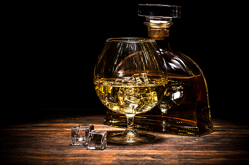 Cognac bottle and glass on the dark background.