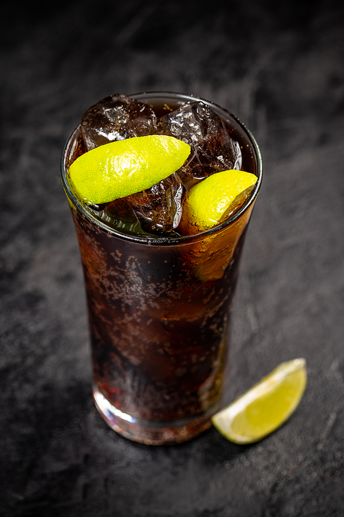 Fresh made Cuba Libre with brown rum, cola and lemon on black background