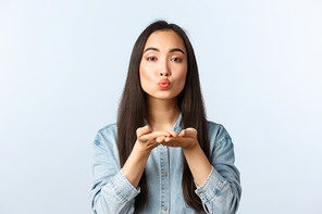 Lifestyle, people emotions and beauty concept. Romantic cute and silly korean girl fold lips and blowing air kiss at camera with caring and dreamy expression, show sympathy and love.