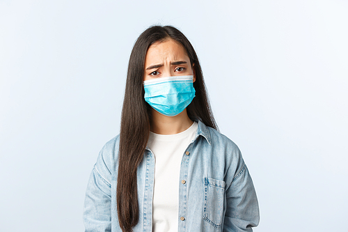 Social distancing lifestyle, covid-19 pandemic everyday life and leisure concept. Upset gloomy asian girl in medical mask looking concerned, showing empathy, frowning, got positive test coronavirus.