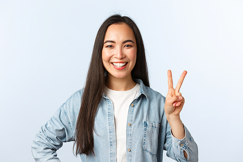 Lifestyle, people emotions and beauty concept. Cheerful cute asian girl, female student in college looking happy, show peace sign and smiling broadly, standing white background.