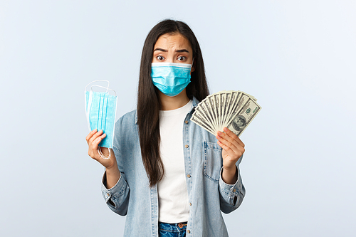 covid-19 pandemic, coronavirus expences and finance concept. Concerned and complicated distressed asian girl pay lots of money for medical mask that are expensive. Copy space