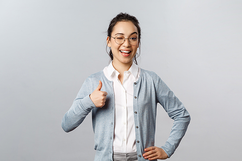 Advertisement, education and people concept. Girl guarantee you will like product. Potrait of lovely asian woman in glasses assure all good, show thumb-up in approval, recommend company service.