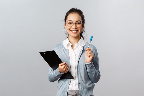 Education, teachers, university and schools concept. Cheerful asian woman in glasses, office lady employee holding pen and clipboard, secretary writing down info during business meeting.