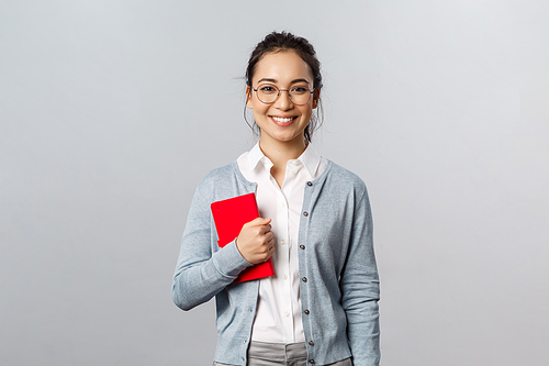 Teaching, education and university lifestyle concept. Good-looking smart young asian female teacher, tutor or student holding red notebook, prepare for lesson, writing down notes in planner.