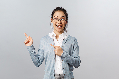 Education, studying and online classes concept. Impressed, happy attractive female entrepreneur in glasses, smiling wondered and amused, pointing looking upper left corner at advertisement.