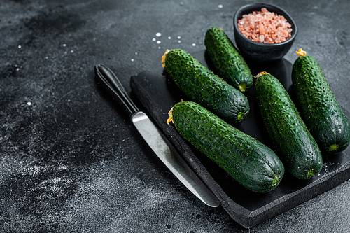 Ripe Green Cucumbers on a marble board. Black background. Top view. Copy space.