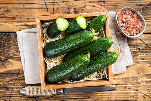 Fresh Green Cucumbers in a wooden box. Wooden background. Top view.