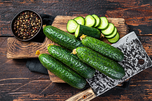Sliced Green Cucumbers on a wooden cutting board. Dark Wooden background. Top view.