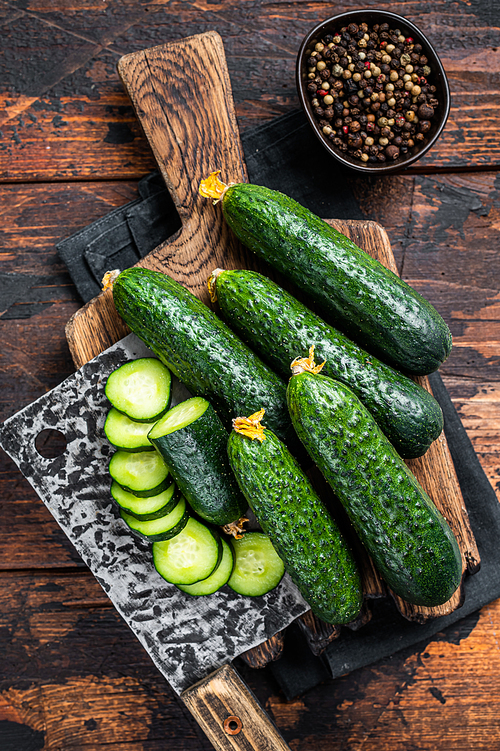 Sliced Green Cucumbers on a wooden cutting board. Dark Wooden background. Top view.