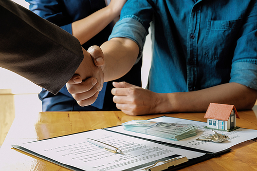 married couple and friendly realtor shaking hands after making real estate deal indoors, above view